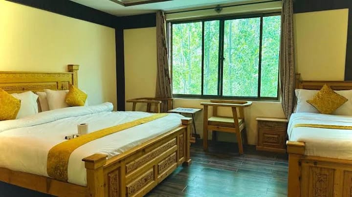 Twin bedroom with carved wooden beds and a forest view at Arcadian Resort Skardu